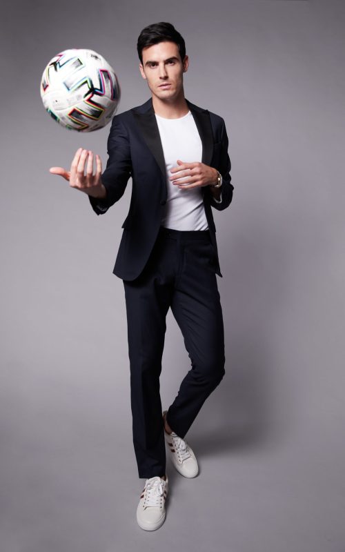 Jason Robert Gaylord in a navy suit, balancing a soccer ball